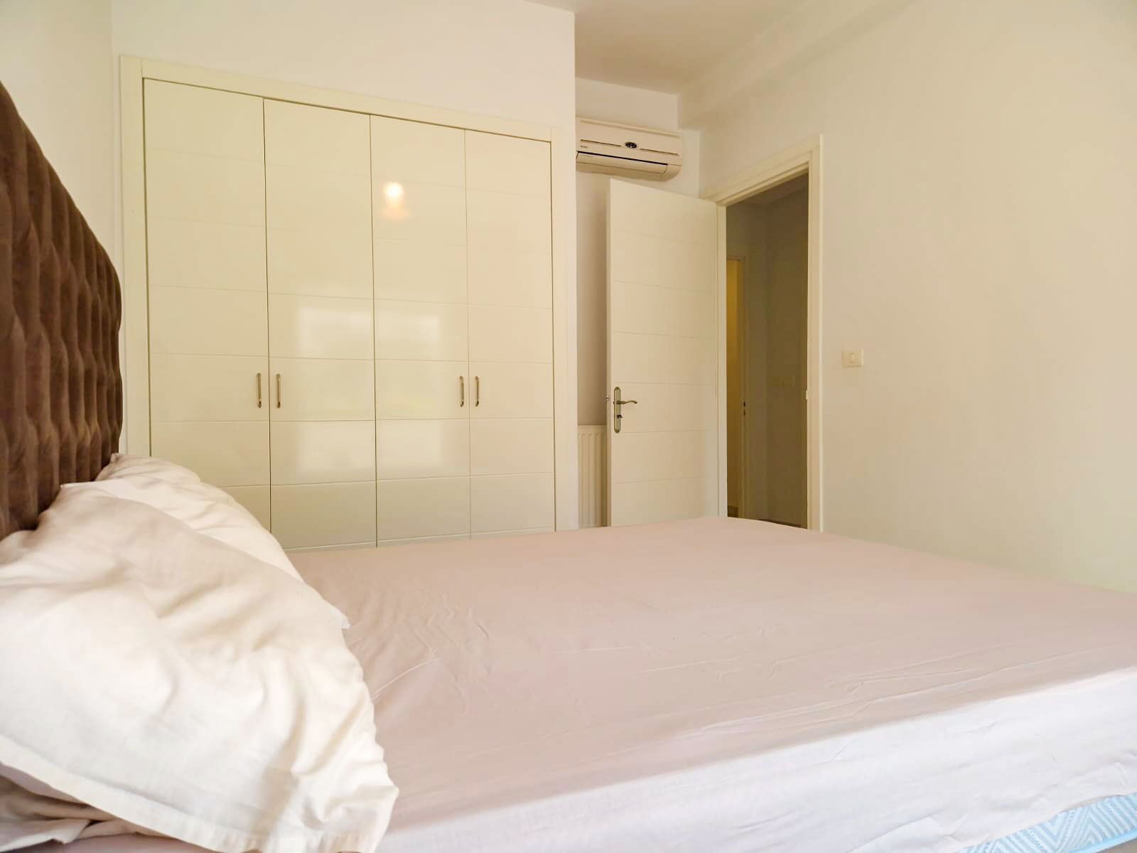 Un dormitorio con cama, armario y aire acondicionado.