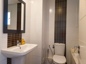A bathroom with a white sink, a toilet, and a shower. - Ennaser Bliss Your Urban Oasis Awaits (Ariana)