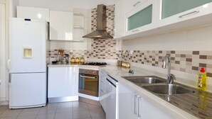 A modern kitchen with white cabinets, a stainless steel sink, a gas stove, and a dishwasher. - Ennaser Bliss Your Urban Oasis Awaits (Ariana)