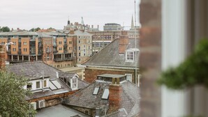 A view of a cityscape through a window, featuring a mix of historic and modern buildings, including a prominent church spire. - Apartment 8 (York)
