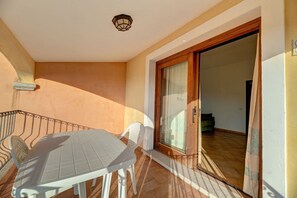 A balcony with a table and chairs, a sliding glass door, and a ceiling light fixture.