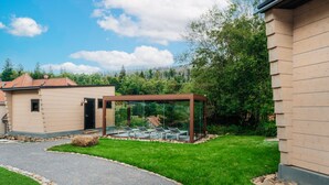 A modern house with a glass-enclosed patio area, a paved driveway, and a well-maintained lawn. - Bodeblick Lodge (Wernigerode)