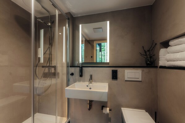 A modern bathroom with a glass-enclosed shower, a white sink, and a mirror above it. - Bodeblick Lodge (Wernigerode)
