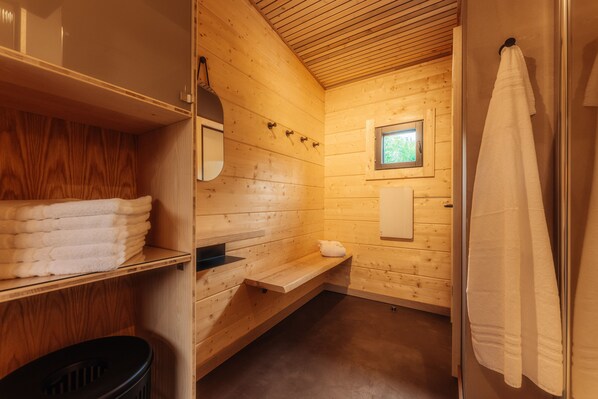 A wooden cabin bathroom with a bench, towel rack, and a small window. - Bodeblick Lodge (Wernigerode)