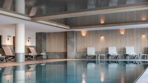 A modern indoor swimming pool with lounge chairs and wall-mounted lights. - Wifi, ski-in/ski-out & foot of the slopes, view resort, fitness, swimming pool, sauna, hammam (La Plagne)