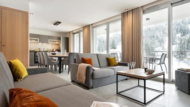 A modern living room with a grey sofa, a coffee table, and a dining area in the background. - Wifi, ski-in/ski-out & foot of the slopes, view ski slopes, fitness, swimming pool, sauna, hammam (Flaine)