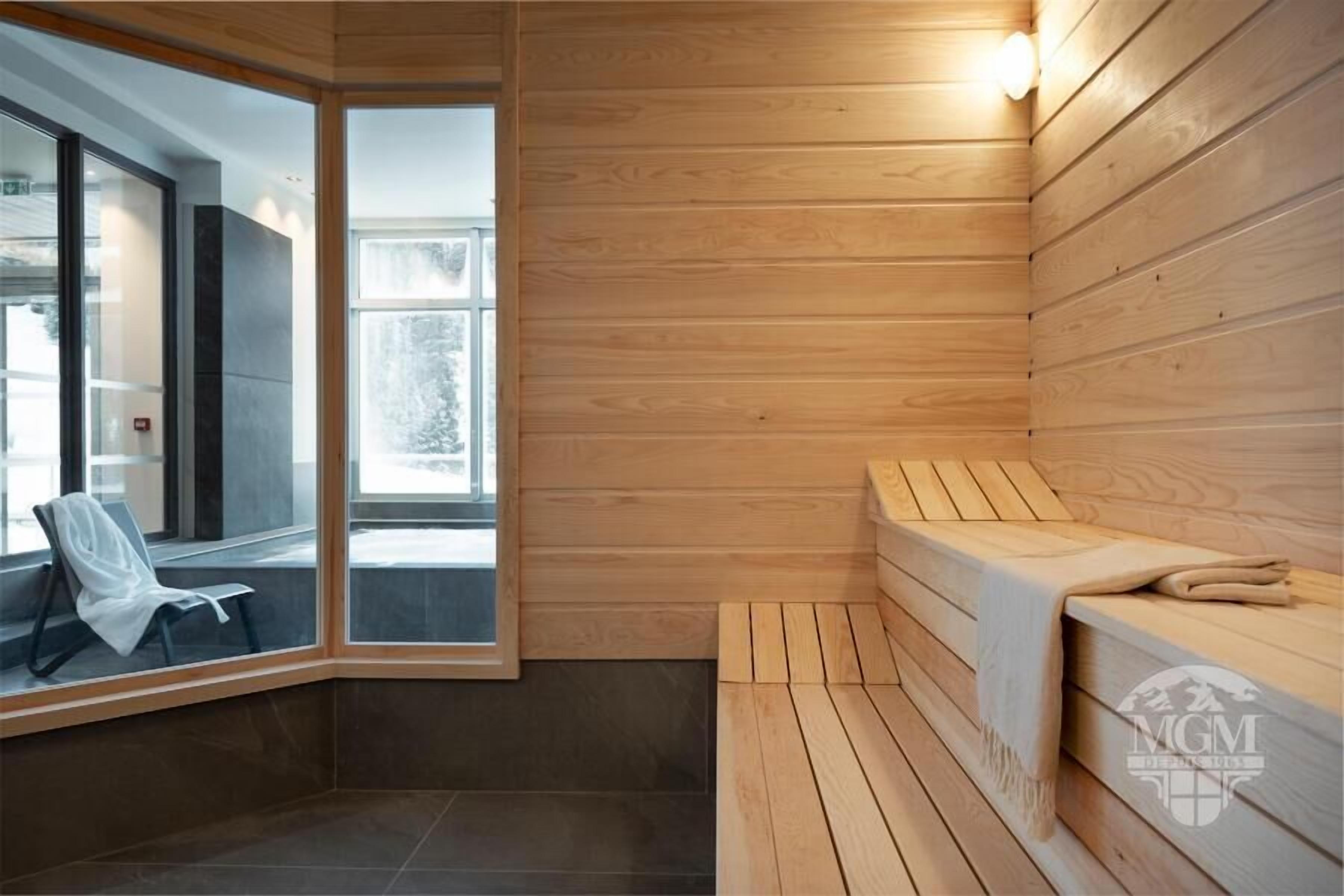 Un cuarto de sauna con paredes de madera, un banco y una puerta de vidrio que da al exterior.