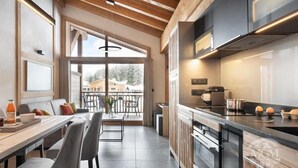Une cuisine moderne dotée d’un grand îlot central, d’appareils électroménagers intégrés et offrant une vue sur l’extérieur.