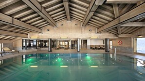 A large indoor swimming pool with a wooden ceiling and seating areas. - Wifi, ski-in/ski-out & foot of the slopes, view mountain, fitness, swimming pool, sauna, hammam (Manigod)