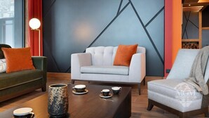 A modern living room with a white sofa, green and white armchairs, and a wooden coffee table with cups and a decorative vase. - Wifi, ski-in/ski-out & foot of the slopes, view mountain, fitness, swimming pool, sauna, hammam (Manigod)