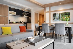 A modern living room with a grey sofa, a coffee table, and a dining area with grey chairs and a table. - Wifi, ski-in/ski-out & foot of the slopes, view mountain, fitness, swimming pool, sauna, hammam (Manigod)