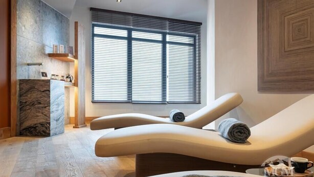 A modern spa room with a curved lounge chair, a marble column, and a large window with blinds. - Wifi, ski-in/ski-out & foot of the slopes, view mountain, fitness, swimming pool, sauna, hammam (Manigod)