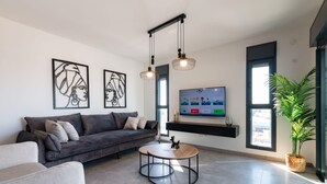Una sala moderna con un sofá gris, una mesa redonda de centro y dos lámparas colgantes.