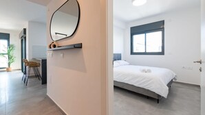 Un dormitorio moderno con una cama, un ventanal grande y un espejo en la pared.