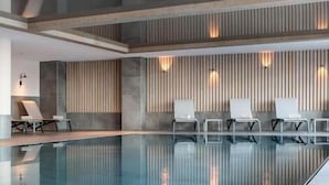 A modern indoor swimming pool with lounge chairs and wall-mounted lights. - Wifi, ski-in/ski-out & foot of the slopes, view mountain, fitness, swimming pool, sauna, hammam (La Plagne)