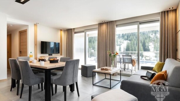 Habitación de hotel moderna con zona de comedor, sofá y televisión.