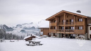 A multi-story wooden lodge with balconies, set against a snowy mountain backdrop. - Wifi, ski-in/ski-out & foot of the slopes, fitness, swimming pool, sauna, hammam, balcony, tv, 45m² (Manigod)