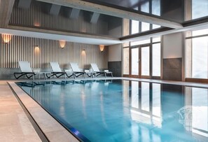 An indoor swimming pool with lounge chairs and a wooden slatted wall. - Wifi, 300m from resort center, Ground floor, view mountain/resort, fitness, swimming pool, sauna (La Plagne)
