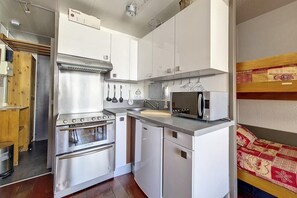 A compact kitchen with stainless steel appliances, a microwave, and a sink. - At the foot of shops, 5th floor, view ski slopes, balcony, tv, ski locker, 24m², Les Menuires (Les Menuires)