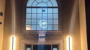 A building entrance with a large arched window and a door with frosted glass panels. - Coastal Retreat - Roomy, Relaxing Heated Pool (Palm Coast)