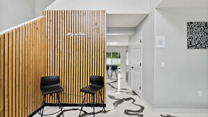 A reception area with a wooden partition, two black chairs, and a patterned floor. - Coastal Retreat - Roomy, Relaxing Heated Pool (Palm Coast)