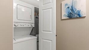 A laundry room with a washing machine, dryer, and a door leading to another room.