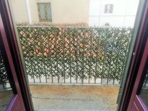 A view through a metal gate with a lattice design, leading to a paved area with trees and a building in the background. - A Magnificent Artist's House in the Heart of Nuoro (Nuoro)