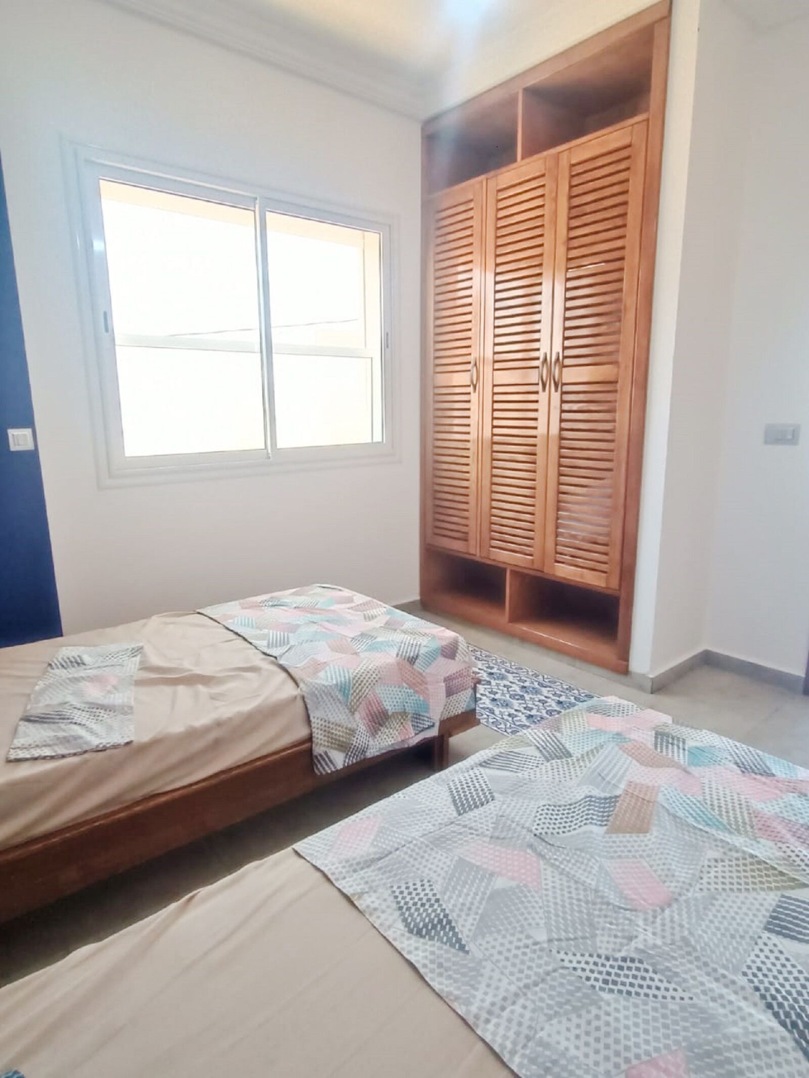 Ein Schlafzimmer mit zwei Betten, einem Kleiderschrank und einem Fenster.