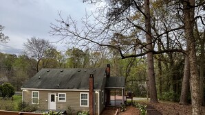 A small, single-story house with a porch, surrounded by trees and a grassy yard. - 5 Points House - Great Location - 3Br2Ba - Early Check-In (Athens)