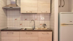 A kitchen with light wooden cabinets, a stainless steel sink, and a white refrigerator. - Glorious Residence Le Pavoncelle Studio No1465 (Santa Teresa di Gallura)