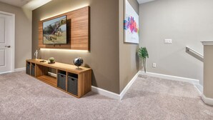 A hallway with a wooden console table, a mounted TV, and a framed artwork on the wall. - Luxury new Home Close to the Parks (Kissimmee)