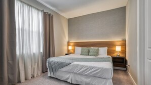 A hotel room with a large bed, two bedside lamps, a wooden headboard, and a view of the city. - Luxury new Home Close to the Parks (Kissimmee)