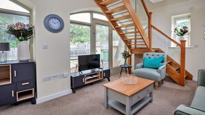 Un salon moderne avec un escalier en bois, un téléviseur, un canapé et une table basse.