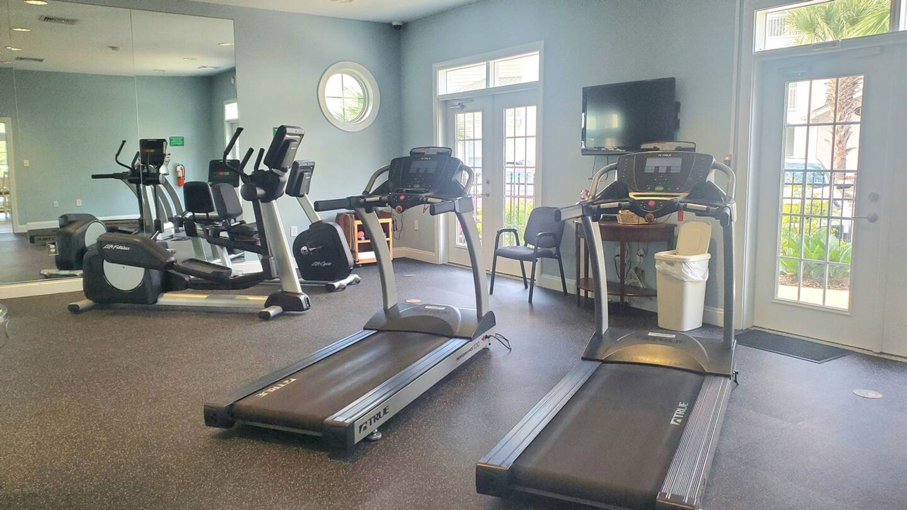 A fitness center with treadmills, elliptical machines, and a television.