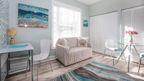 Una sala de estar moderna con sofá, sillones, una mesa de vidrio, un ventanal grande y un elemento decorativo en la pared.