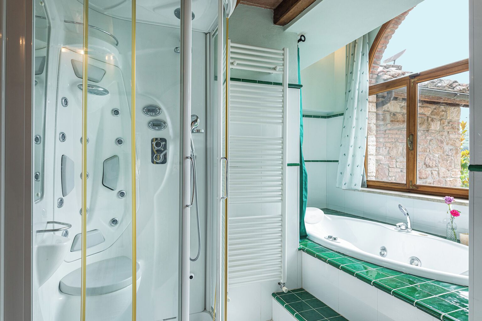 A modern bathroom with a glass-enclosed shower, a bathtub, and a sink with green tiles.