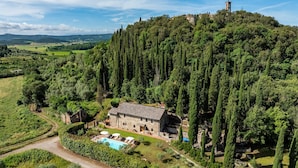 Une villa en pierre dotée d’une piscine, entourée d’une végétation luxuriante et offrant une vue panoramique depuis le sommet d’une colline.