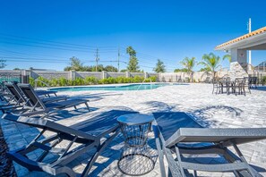 A poolside area with lounge chairs, a small round table, and a covered seating area.