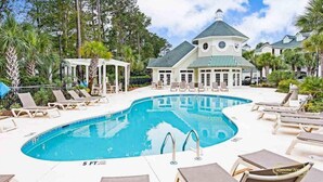 Area piscina con sedie a sdraio, un gazebo e un edificio con tetto verde.