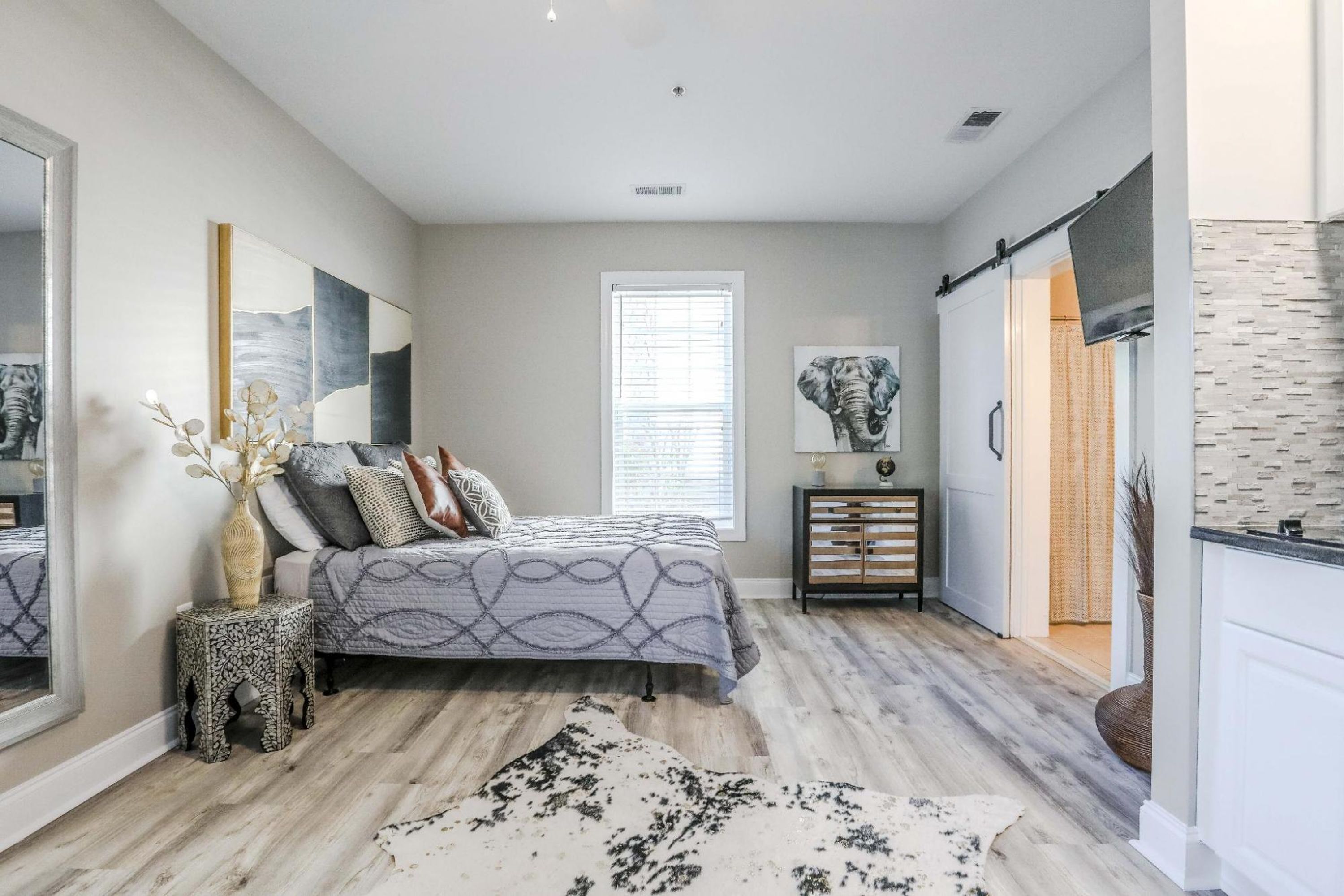 A bedroom with a bed, a nightstand, a window, and a wall-mounted artwork.