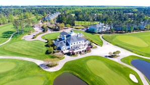 Un'ampia casa moderna con un generoso giardino anteriore, un campo da golf e uno stagno.