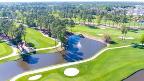 An aerial view of a golf course with a pond, sand bunkers, and surrounding trees. - Mini Oasis Studio 10 Min to All Myrtle Beach (Myrtle Beach)