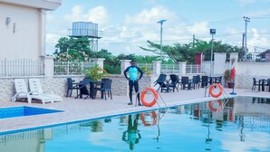 A swimming pool area with lounge chairs and a person standing by the pool. - Eden Hotels Ltd (Eket)