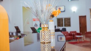 A room with a reflective surface, a patterned vase with a plant, and red furniture. - Eden Hotels Ltd (Eket)