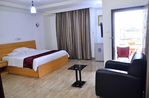 A hotel room with a bed, a small table, a chair, and a view of the outside. - Eden Hotels Ltd (Eket)