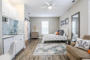 A compact bedroom with a bed, a sofa, a small desk, and a kitchenette. - My Vitamin Sea Quaint Studio Myrtle Beach SC (Myrtle Beach)