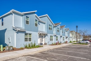 Une rangée de maisons de ville bleu clair, avec un parking devant.