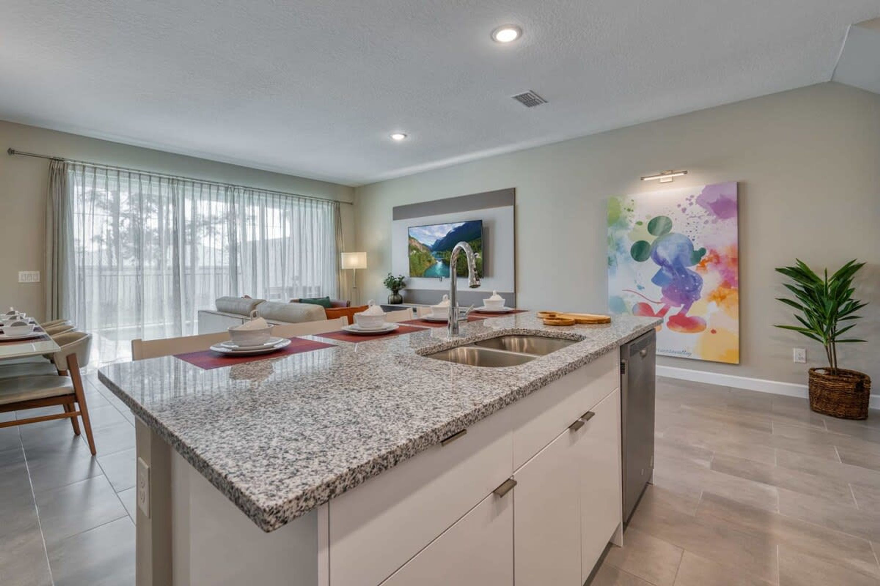 Una cocina moderna con encimeras de granito, lavavajillas integrado y comedor con mesa y sillas.