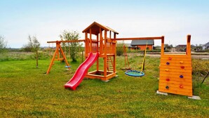 Un parque infantil de madera con tobogán y estructura para escalar.