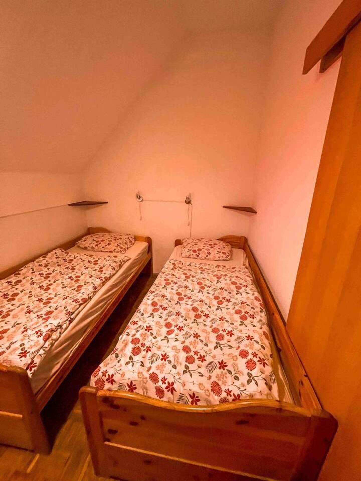 Ett litet, ombonat rum med två enkelsängar, trägavlar och ett sluttande tak.